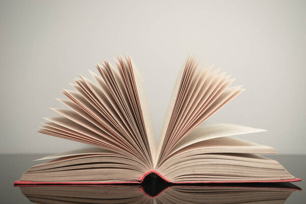 Beautiful open book on a gray and glass table background.