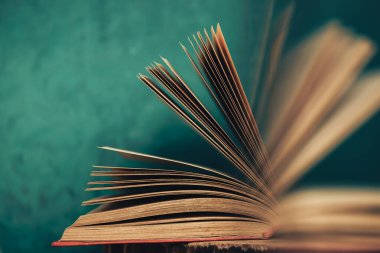 Eski ahşap bir masada güzel soyut açık bir kitap ve arkasında yeşil bir duvar..