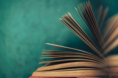 Eski ahşap bir masada güzel soyut açık bir kitap ve arkasında yeşil bir duvar..