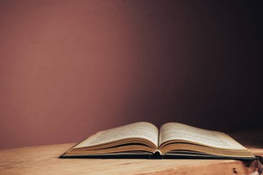 Güzel, açık, antika bir kitap. Tasarım için model arka planı. Kırmızı ahşap masa ve kırmızı duvar arkaplanındaki kitap..