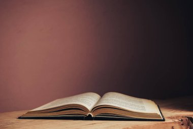 Güzel, açık, antika bir kitap. Tasarım için model arka planı. Kırmızı ahşap masa ve kırmızı duvar arkaplanındaki kitap..