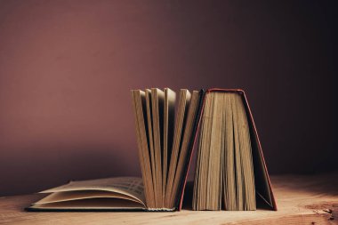 Antika kitaplar. Tasarım için model arka planı. Kahverengi ahşap masa ve kırmızı duvar arkaplanındaki kitap..