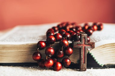 Kutsal İncil 'i ve boncukları eski yuvarlak bir masanın üzerine kapat. Güzel kırmızı duvar arkaplanı.