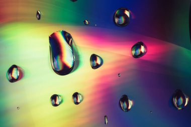 Holografik efektin çok renkli su damlasını kapatın. Tasarım için arkaplan deseni. 