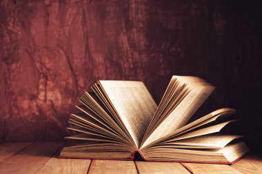 Kapat güzel antik açık eski kitap kırmızı ahşap bir masa ve arkasında koyu kırmızı duvar.
