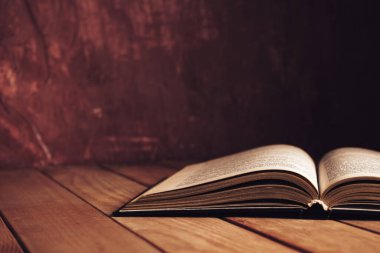 Kapat güzel antik açık eski kitap kırmızı ahşap bir masa ve arkasında koyu kırmızı duvar.