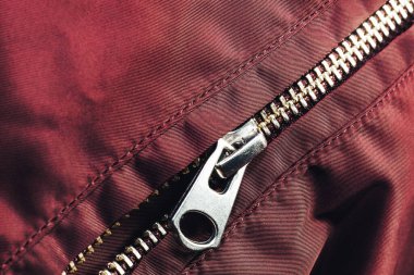 Kırmızı kumaş arka plandaki fermuarı dikişle kapat. Makro fotoğrafçılık arka plan materyal görünümü.