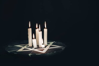 Altı yanan mum ve Davut Yıldızı siyah bir arkaplanda.