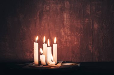 Altı yanan mum ve kırmızı arka plan duvarında Davut Yıldızı..