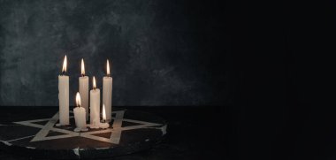 Altı yanan mum ve Davut Yıldızı koyu gri arka plan duvarına karşı.