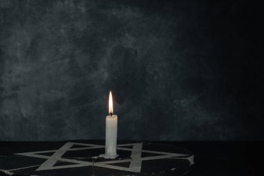 Bir yanan mumla Davut Yıldızı 'nı koyu gri arka plan duvarına yaklaştır..