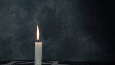 Bir yanan mumla Davut Yıldızı 'nı koyu gri arka plan duvarına yaklaştır..