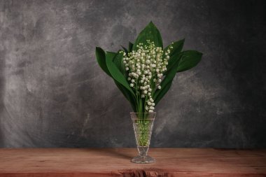Convallaria majalis kırmızı ahşap bir masada Güzel gri duvar arkaplanı.