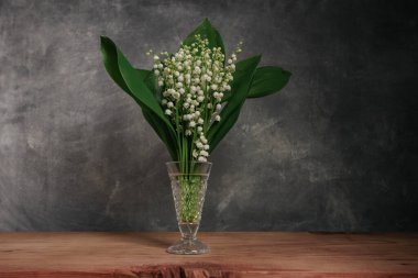 Convallaria majalis kırmızı ahşap bir masada Güzel gri duvar arkaplanı.