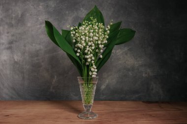 Convallaria majalis kırmızı ahşap bir masada Güzel gri duvar arkaplanı.