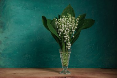 Convallaria majalis kırmızı ahşap bir masada Güzel yeşil duvar arka planı.