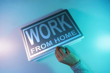 Gümüş bir dizüstü bilgisayar gecesinde, masa arkaplanındaki renkli ışıkta kelimeler evden işe yarar. Üst görünüm.