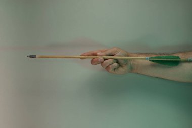 Renkli ışıkta eski yeşil okları tutan el. Güzel eski ok, neon ışıkta minimumda. Minimalizm retro tarzı konsept. Tasarım için arkaplan deseni. 