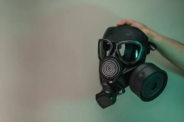 Hand hold black old gas mask in the color light. Beautiful old minimal in neon light. Minimalism retro style concept. Background pattern for design.