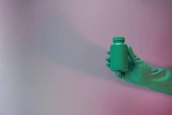 Beautiful hand hold Green bottle for pills in the color light. Beautiful old minimal in neon light. Minimalism retro style concept. Background pattern for design.