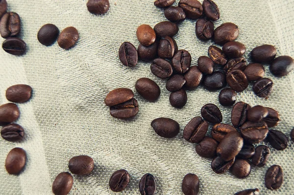 Granos de café esparcidos en un mantel estampado — Foto de Stock