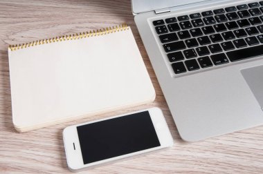 Not Defteri, dizüstü bilgisayar ve ahşap masa üstünde hareket eden telefon