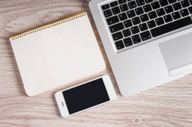 Not Defteri, dizüstü bilgisayar ve ahşap masa üstünde hareket eden telefon