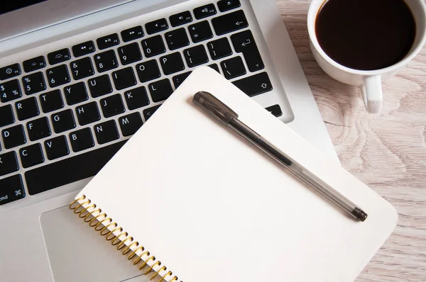 Bloc de notas, portátil y taza de café en la mesa de madera — Foto de Stock