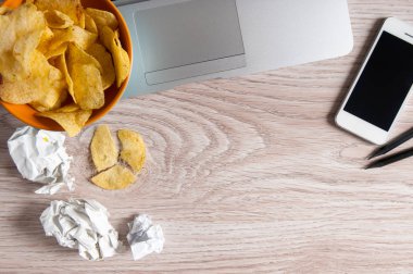 Dizüstü bilgisayar, buruşuk kağıt ve ahşap masa üzerindeki fişlere kase çalışma alanı. Kötü alışkanlıkları kavramı