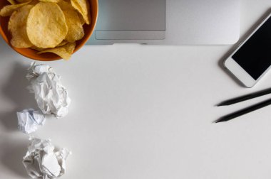 Dizüstü bilgisayar, buruşuk kağıt ve ahşap masa üzerindeki fişlere kase çalışma alanı. Kötü alışkanlıkları kavramı