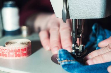 Yaşlı terzi dikiş makinesi üzerinde çalışıyor