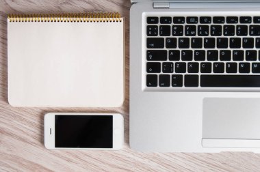 Not Defteri, dizüstü bilgisayar ve ahşap masa üstünde hareket eden telefon
