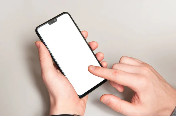 男子手拿着新的现代智能手机手机 用空白的显示屏触摸着他的手指 用灰色的桌子背景隔开 — 图库照片