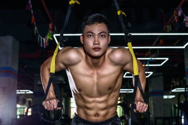 Genç çekici Çin atletik bir adam Trx ile salonda Çin Hong Kong eğitim büyük seksi kaslar ile
