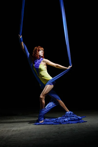 Beautiful young athletic girl posing with gorgeous blue aerial silks.