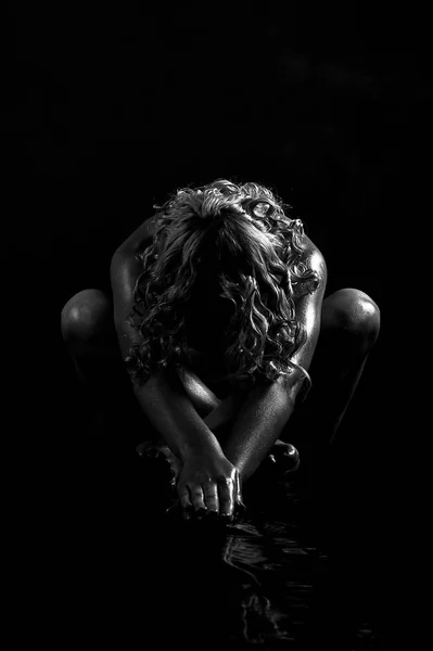 美丽性感裸女金发女郎 坐在地板上的黑暗 她伸展双臂向前 在地板上的水 她的倒影 很迷人黑白照片 — 图库照片