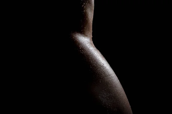 Kunst foto van mooie sexy naakte vrouwelijk lichaam, in olie met druppels water op het lichaam, tere bochten van de naakte taille en heupen prachtig in de duisternis. — Stockfoto