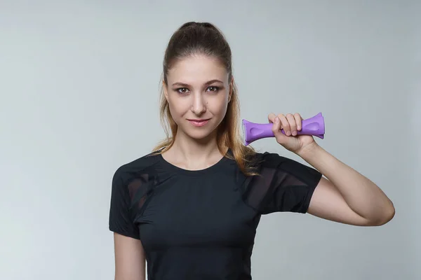 Mükemmel bir siyah t shirt esmer saçlı genç güzel seksi kadın fotoğraf Studio gri arka plan üzerinde mor dumbbell ile poz. Fitness spor sağlık sağlık modeli fotoğraf çekim.