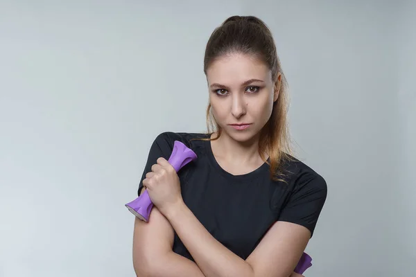 Mükemmel bir siyah t shirt esmer saçlı genç güzel seksi kadın fotoğraf Studio gri arka plan üzerinde mor dumbbell ile poz. Fitness spor sağlık sağlık modeli portre fotoğraf çekim