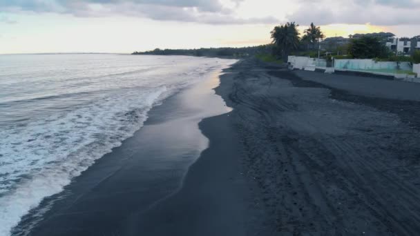 海洋海滩的空中视频与黑色的沙子和波浪在巴厘岛日落与美丽的快乐年轻女性模特牛仔裤短裤和灰色 T恤衫 拍摄视频4K 从上面的飞机 美妙的景色 — 图库视频影像