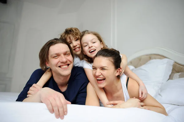 Los padres jóvenes y su hijo y su hija juegan en el dormitorio Fotos de stock libres de derechos