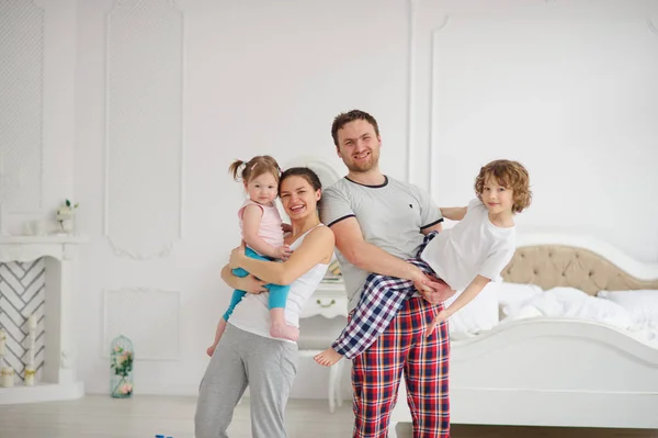 Los padres jóvenes y su hijo y su hija juegan en el dormitorio Imagen de archivo