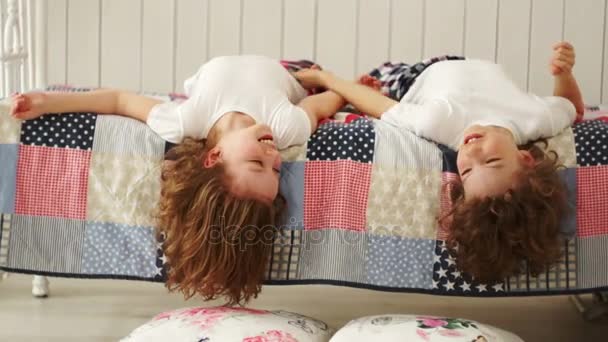 Feliz irmão e irmã brincando e rindo na cama pendurando a cabeça para baixo . — Vídeo de Stock