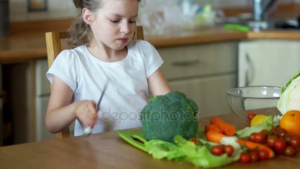Das kleine Mädchen in der Küche schneidet den Brokkoli. — Stockvideo