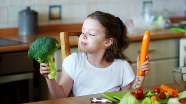 Söt flicka håller i händerna på broccoli och morötter. — Stockvideo