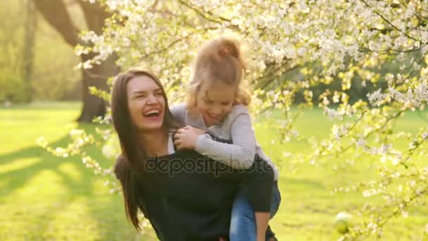 Joven madre e hija en jardín de flores . — Vídeo de stock