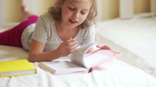 Menina lendo livro deitado na cama . — Vídeo de Stock