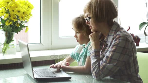 Babcia i wnuk z zainteresowaniem spojrzeć na ekran laptopa. — Wideo stockowe