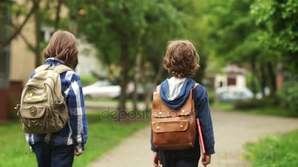 Dois meninos e meninas estão voltando para casa depois da escola. A rapariga apanha os rapazes e abraça-os. Amigos da escola, amor de infância, para acompanhar a casa. Abraços amigáveis — Vídeo de Stock