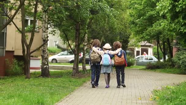 Two boys and girl are returning home after the school. School friends, childhood love, to accompany home. Friendly hugs — Stock Video